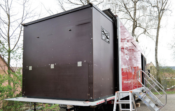 Foto eines Lastwagens von hinten mit ausgefahrenem Holzkasten auf der Beladungsfläche