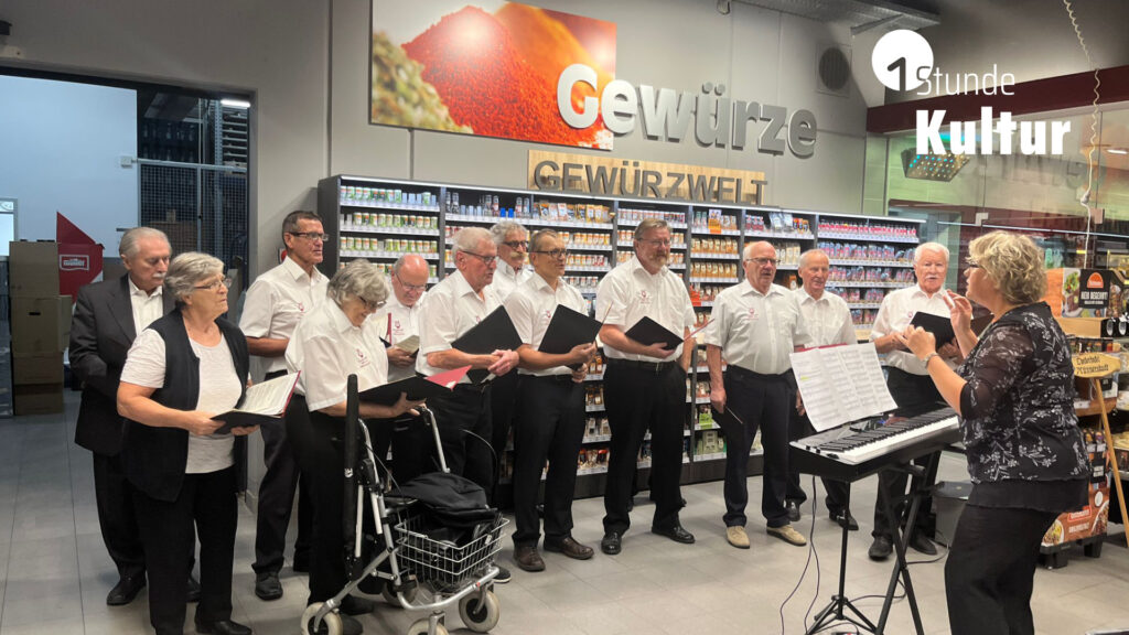 Ein Chor singt in einem Supermarkt vor dem Gewürzregal