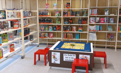 Regalreihen mit Kinderbüchern und ein Spieletisch für Kinder