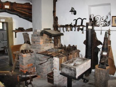 Blick in eine alte Schmiede mit Feuerstelle und handwerlichen Utensilien