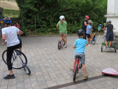 Kinder fahren Spaß- und Geschicklichkeitsräder auf einem gepflasterten Hof