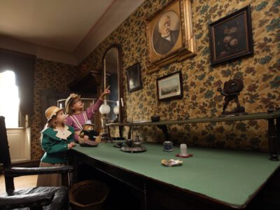 Kinder in historischer Kleidung zeigen auf Porträts an einer Wand im Museum Obere Saline
