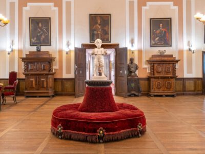 Ausstellungsraum mit alten Möbeln und Statue in der Mitte