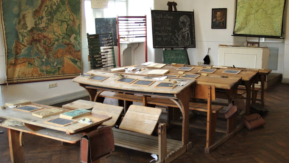 Historischer Klassenraum mit Tafeln, Landkarten und Schultischen
