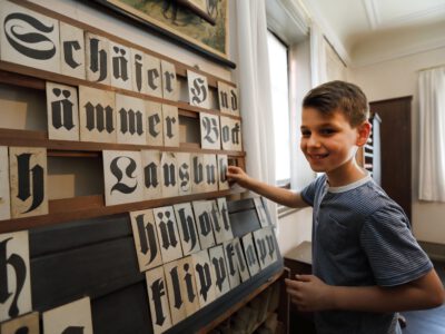 Ein Junge sortiert Buchstaben in alter Schrift.
