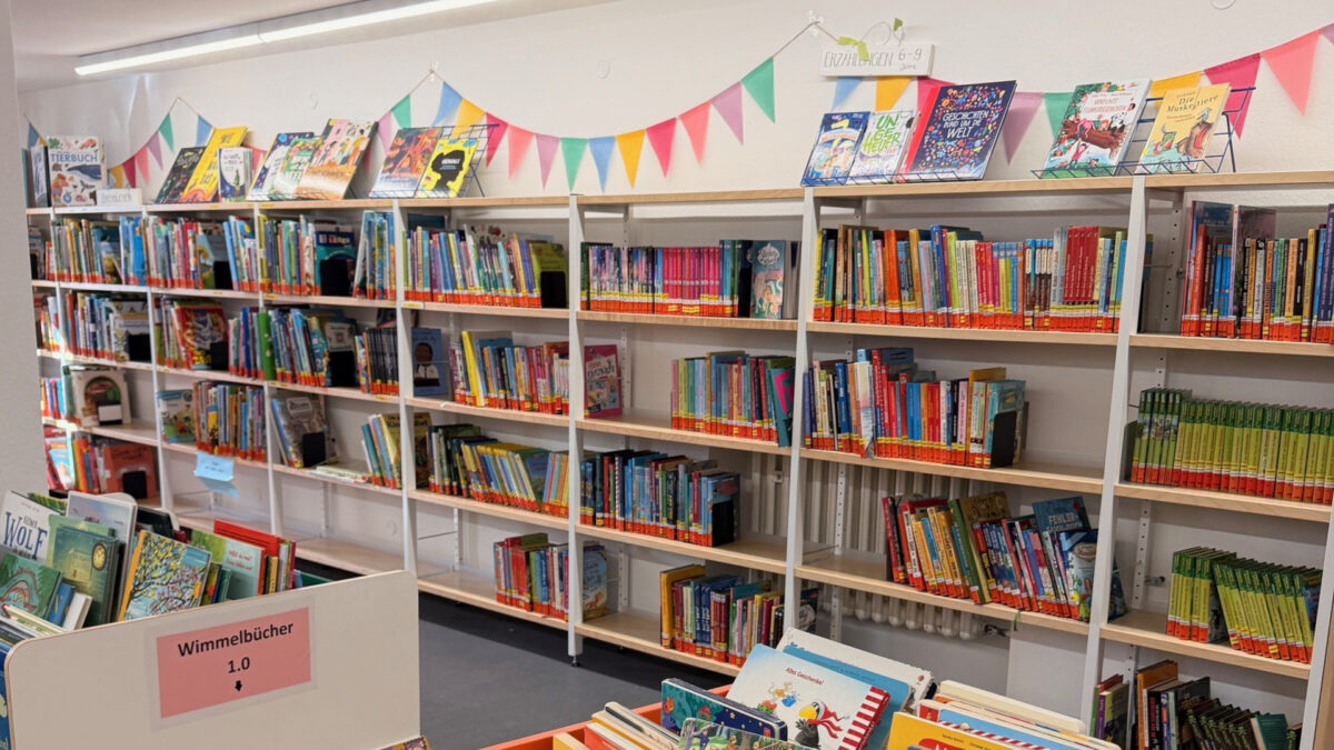 Büchertisch und Bücherregale mit Kinderbüchern; Wimpelkette an der Wand
