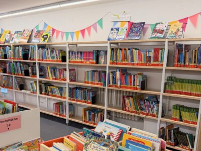 Büchertisch und Bücherregale mit Kinderbüchern; Wimpelkette an der Wand