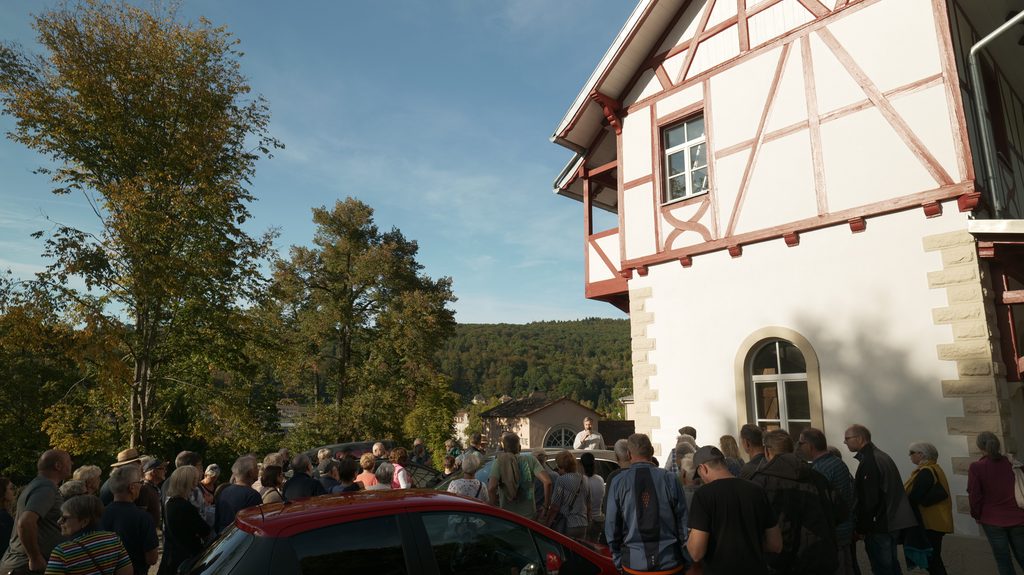 Viele Menschen hören bei einer Führung vor einem historischen Fachwerkshaus zu