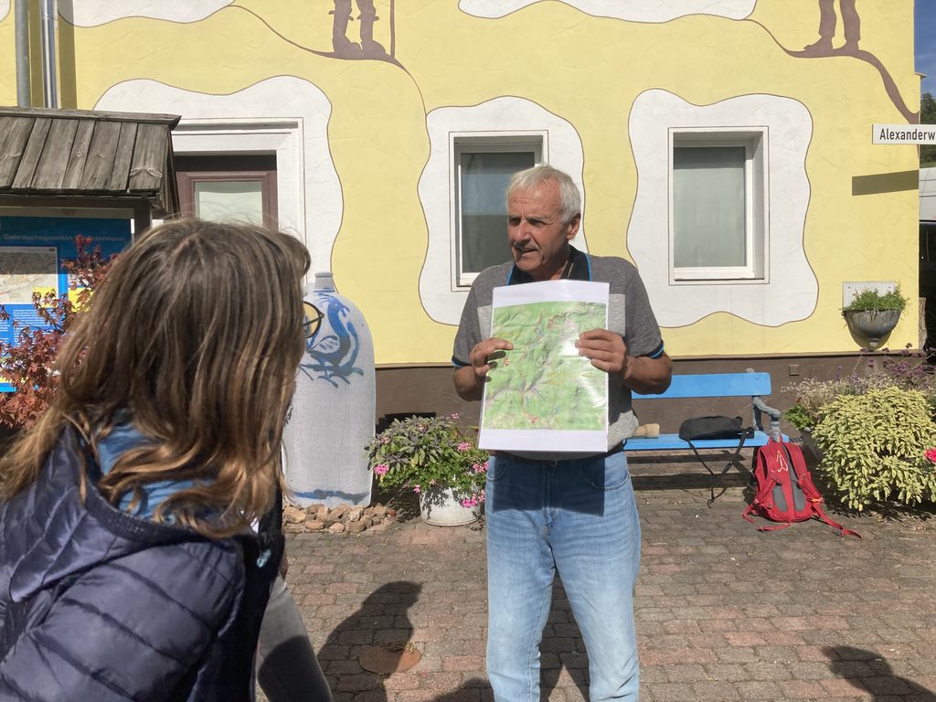 Ein Mann hält ein Schild in der Hand und gibt Hintergrundinformationen. Im Vordergrund: der Hinterkopf einer interessierten Zuhörerin.