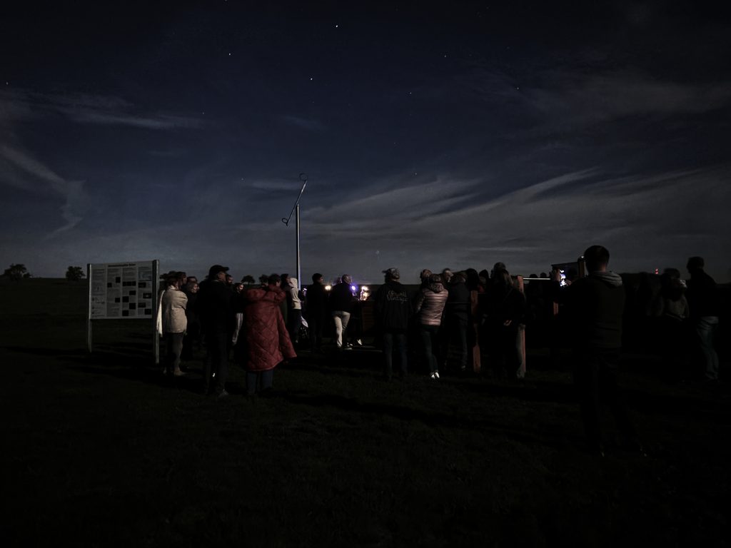 Menschen stehen auf einem dunklen Bild vor einem Himmel mit Sternen